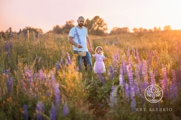 Dad and daughter in a lupine field at sunset